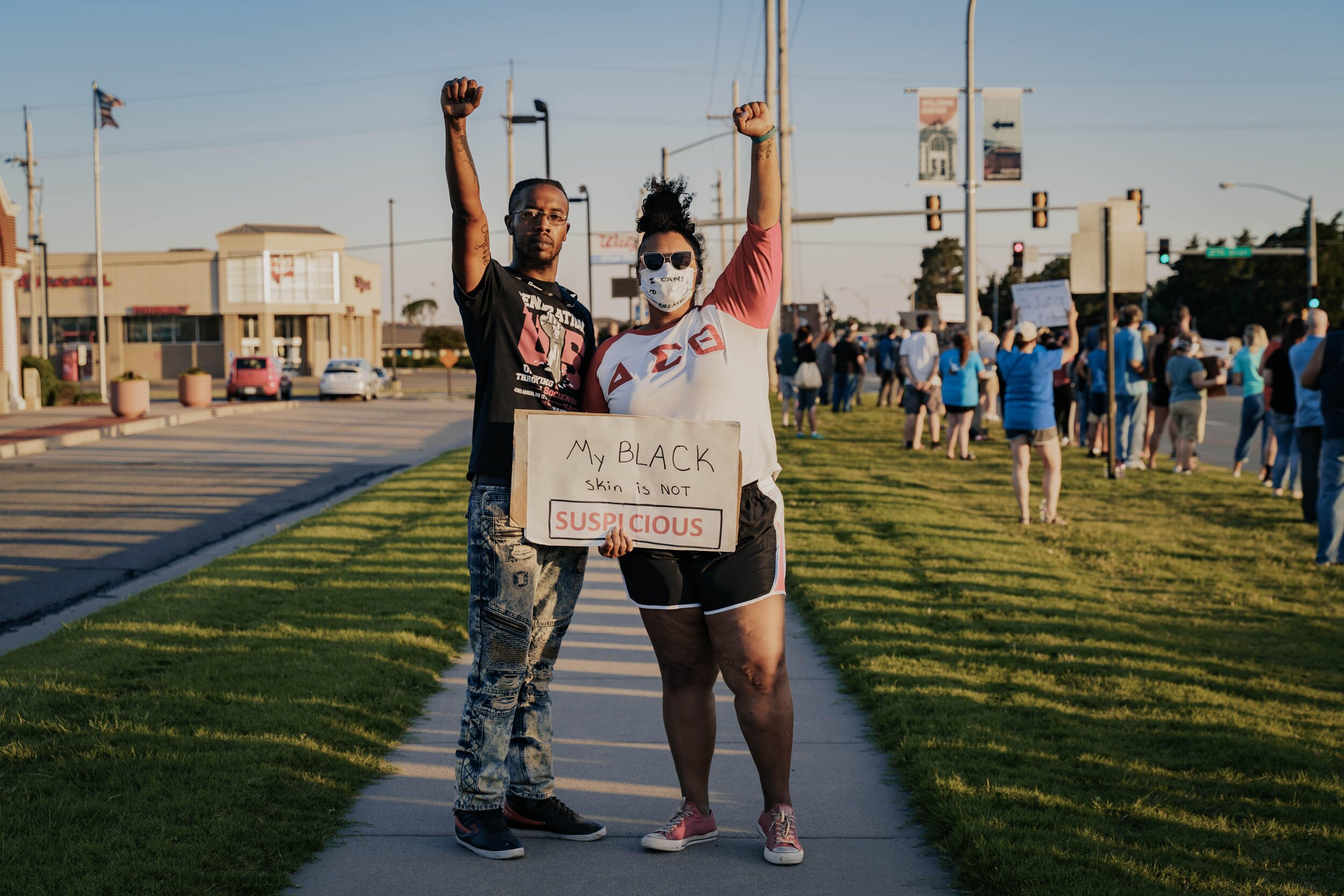 protesters standing with fist in the air with poster reading "My black skin is not suspicious."