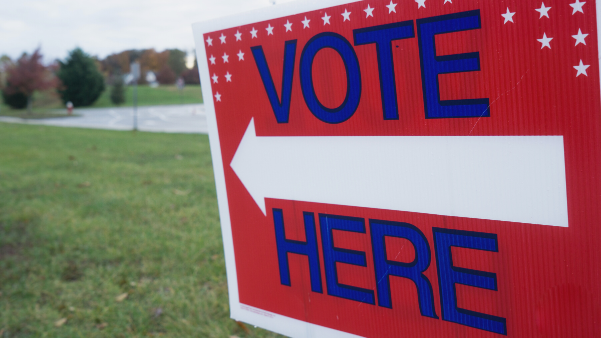An read white and blue VOTE HERE sign outside a voting location.
