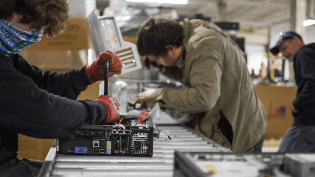 Two people take apart desktop computers, which will then be refurbished and sold at a lower cost to families who need devices in Kansas City.