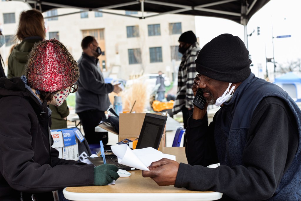 A case manager helps an unhoused man, Raymond Denson, apply for an ID.