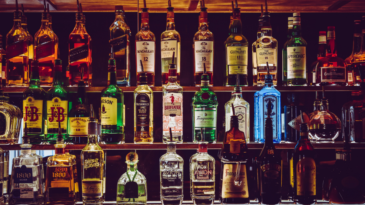 Bottles of liquor on three shelves with low lighting