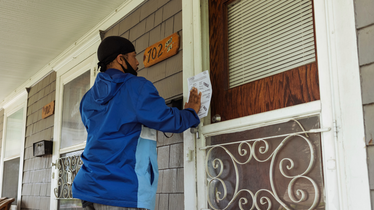 Lamon Lewis places a flyer with vaccine information on a home near downtown Kansas City, Kansas, on May 21, 2021. Photo by Chase Castor/The Beacon
