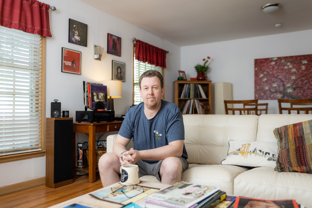 Brandon Smith sitting in his living room in the house he bought in north Kansas City. He experienced the ups and downs of Kansas City's housing market.