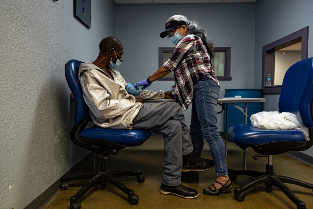 Volunteer nurse Regina Ancola checks the blood pressure of a patient at Street Medicine KC's weekend medical clinic.
