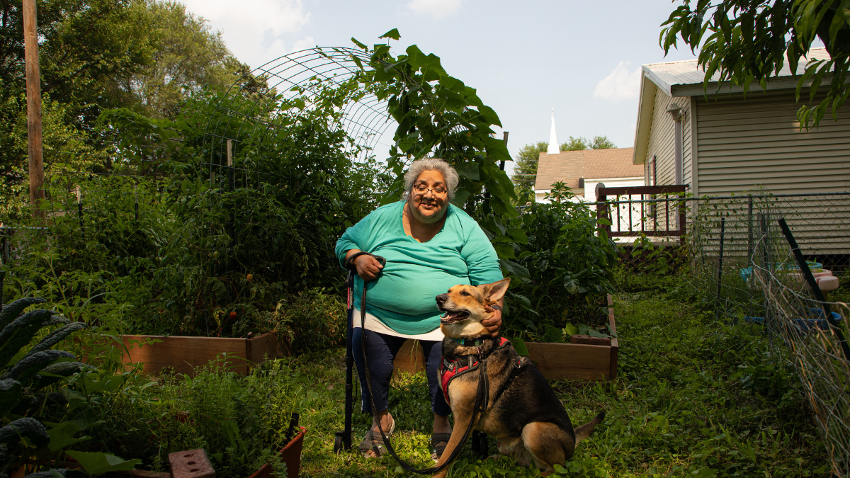 Louise Lynch and her dog sit in her garden in Kansas City, Kansas. She's faced the threat of a utility shutoff in recent months.