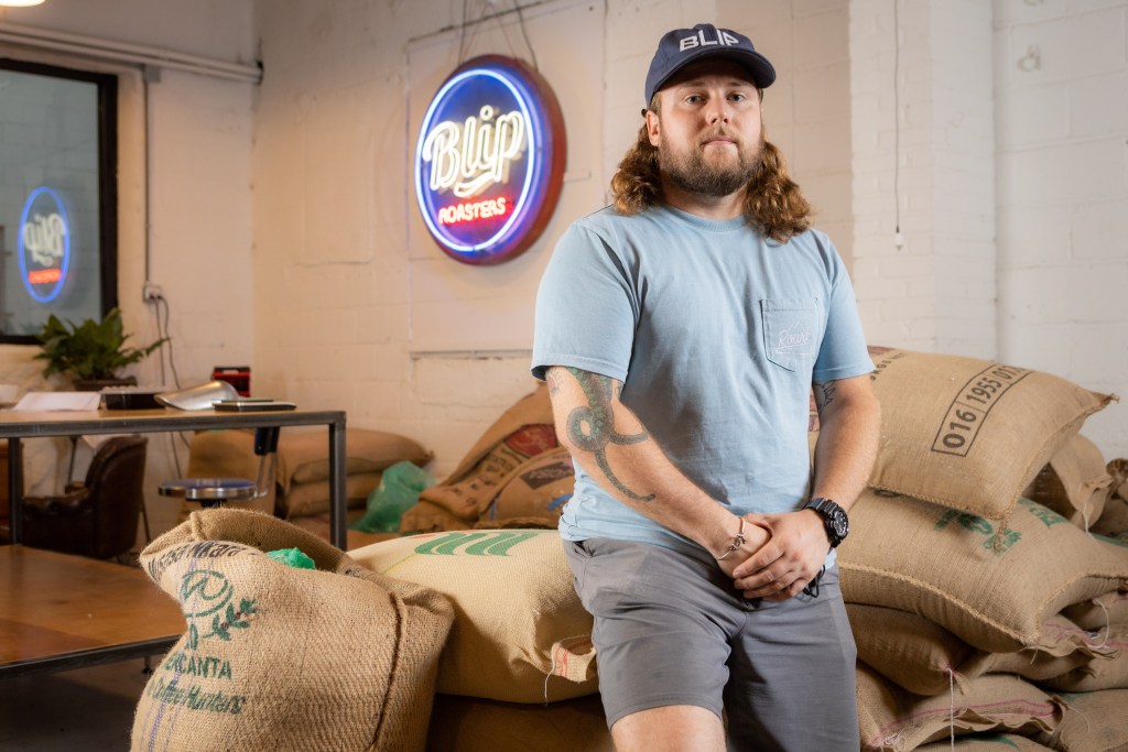 Ian Davis stands in front of a bag of coffee beans at Blip Coffee Roasters in the West Bottoms.