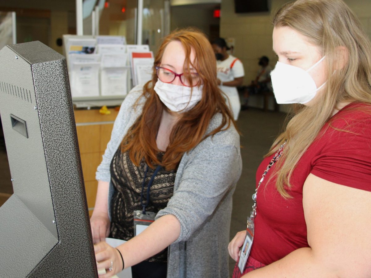 Clerks Stephanie Crump (right) and Ursela Hemman use one of four new kiosks for residents to access rent relief and other services from Wichita’s Housing & Community Services Department. (Matt Hennie/The Beacon)