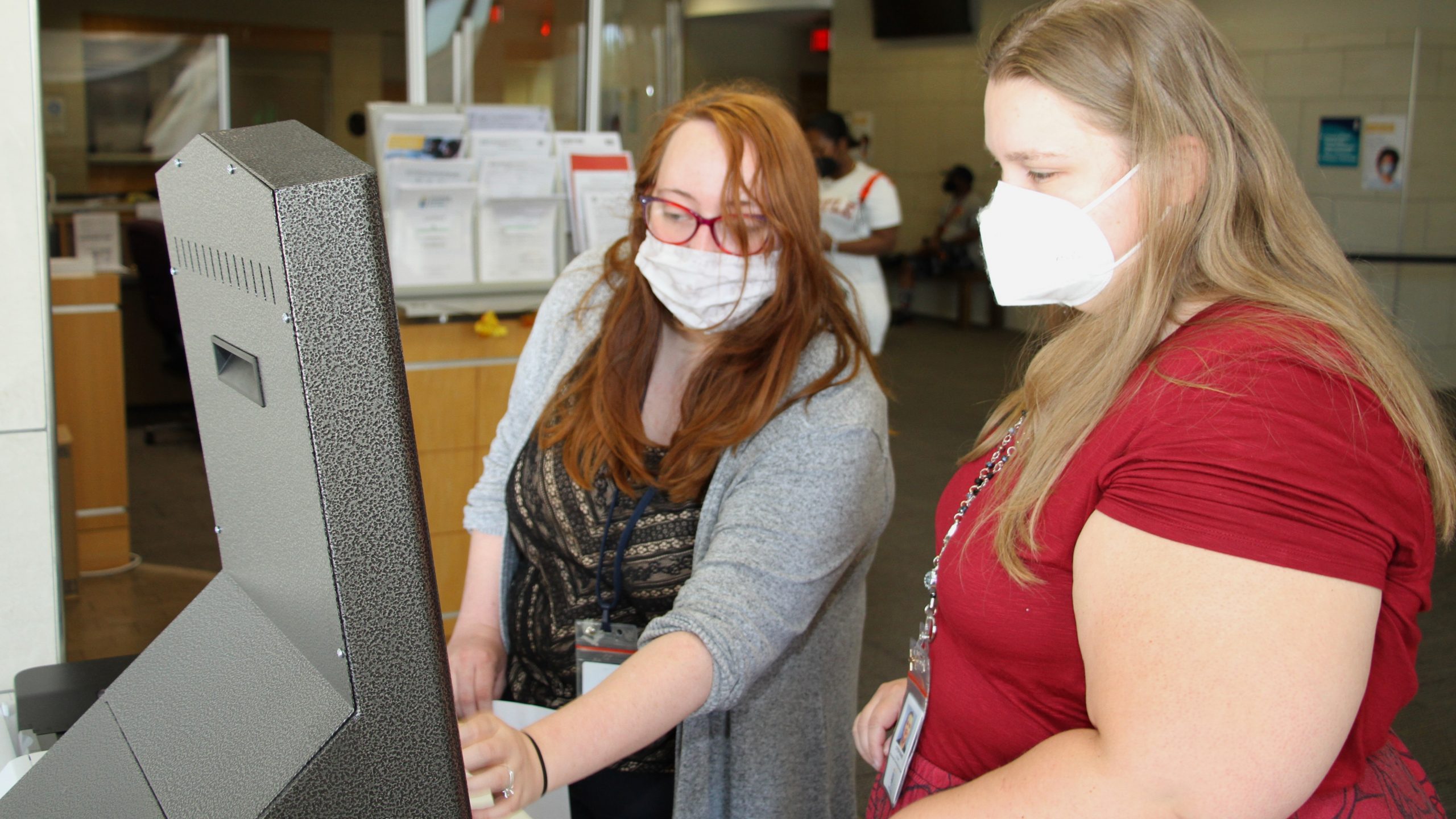 Clerks Stephanie Crump (right) and Ursela Hemman use one of four new kiosks for residents to access rent relief and other services from Wichita’s Housing & Community Services Department. (Matt Hennie/The Beacon)