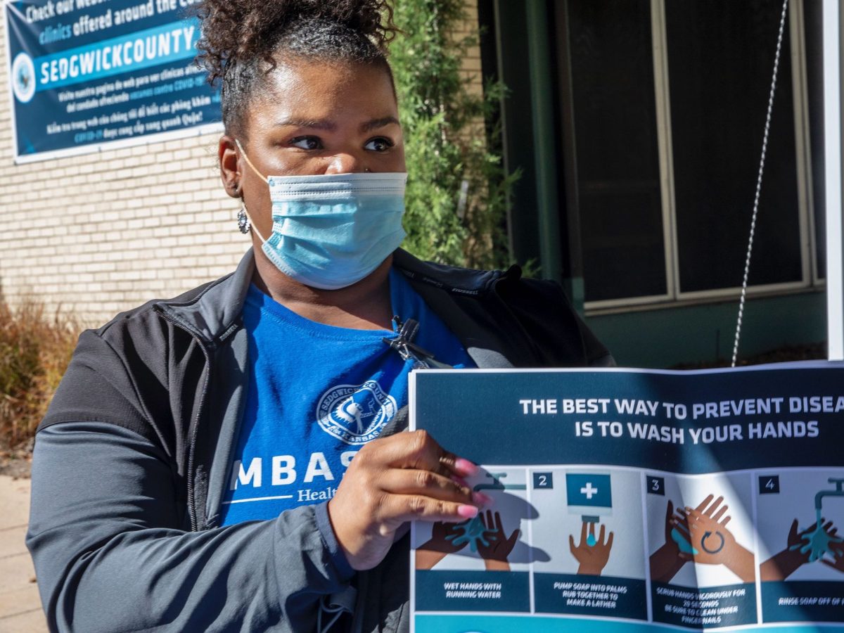 Stacey Roundtree, a Sedgwick County COVID Ambassador, holds educational materials from backpacks given to participants at the COVID-19 Vaccine Incentive Clinic at the Sedgwick County Health Department on Oct. 16. (Fernando Salazar/The Beacon)