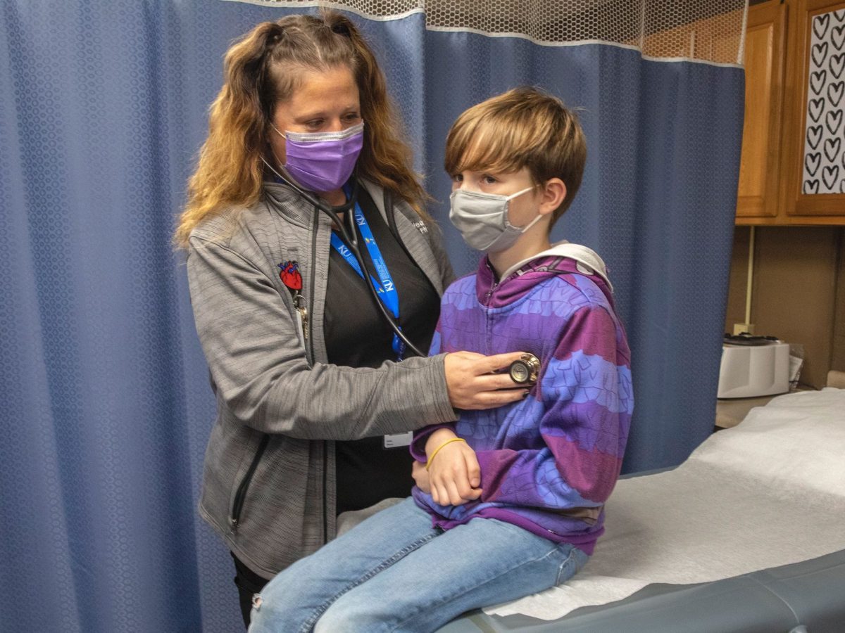 Registered nurse Krista Weaver and her nephew Les Weaver demonstrate how students receive medical care at Haysville USD 261’s school-based health clinic. (Photo illustration by Fernando Salazar/The Beacon)