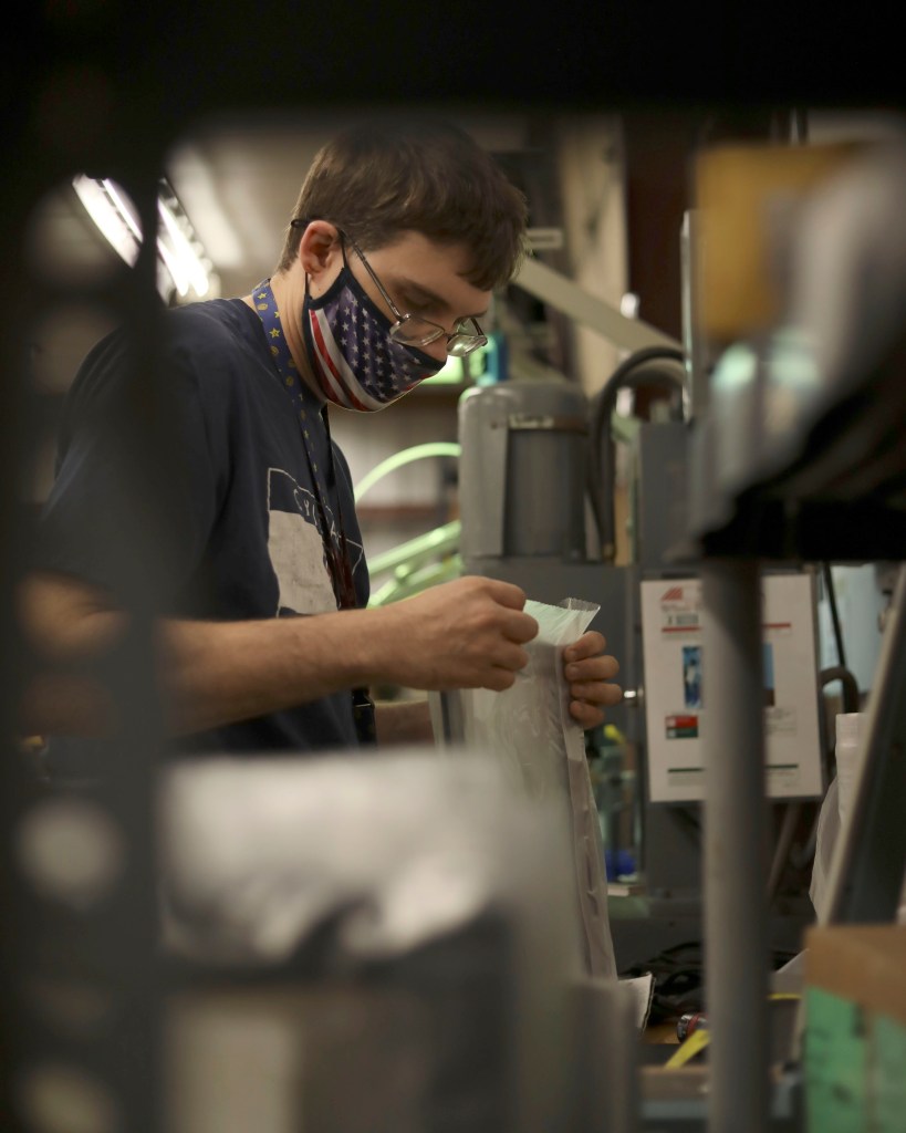 A person seals a bag with parts of a breaker box at a sheltered workshop in Columbia, Missouri. 