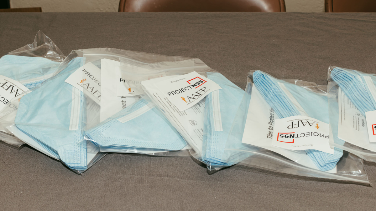 Packets of masks spread across a table. Each pack contains 10 masks and is labeled "Project N95" and "AAFP."