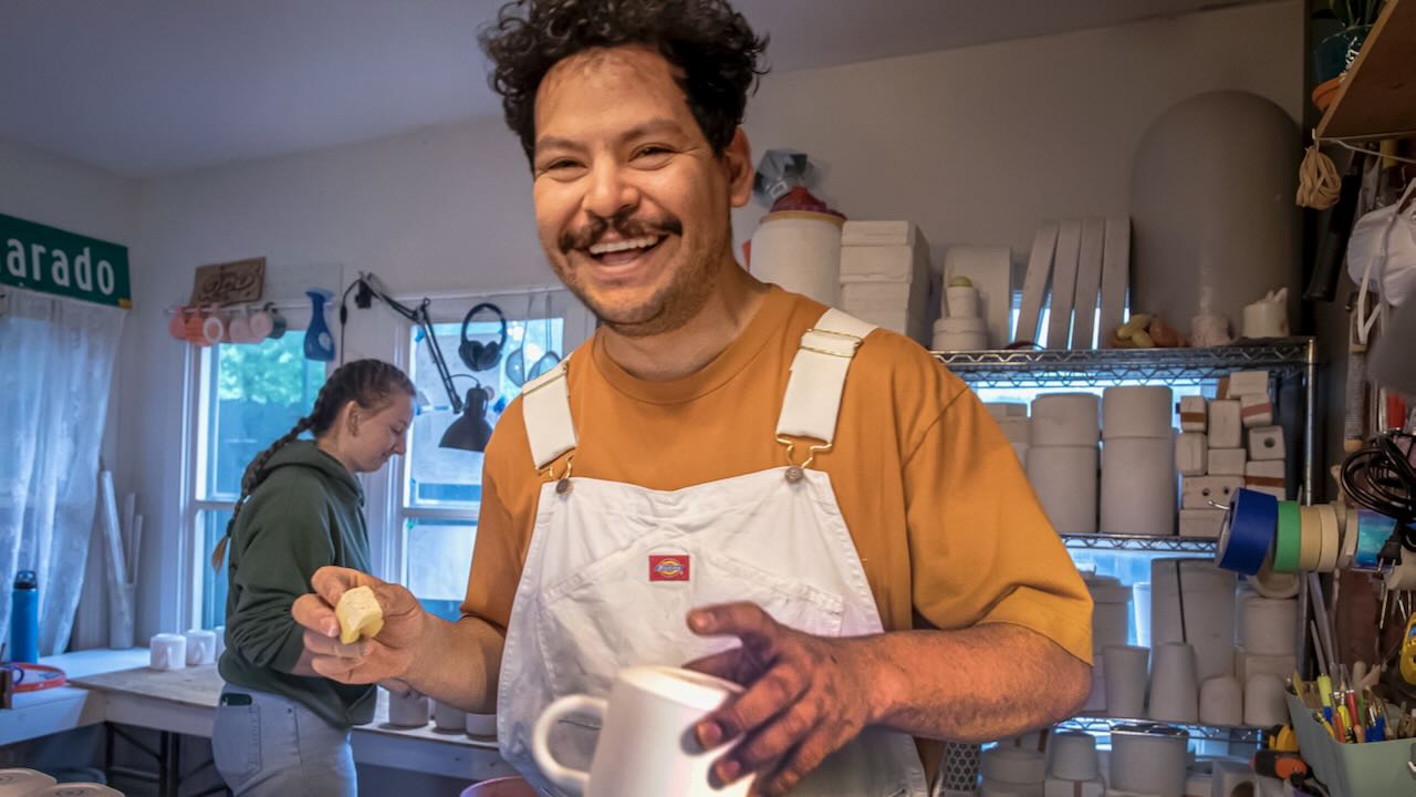 Armando Minjárez smiling at camera wearing white overalls.