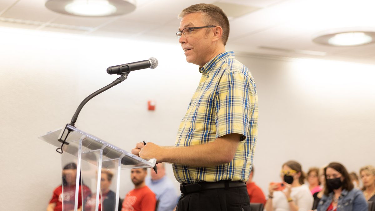 A man speaks at a podium during a school board meeting