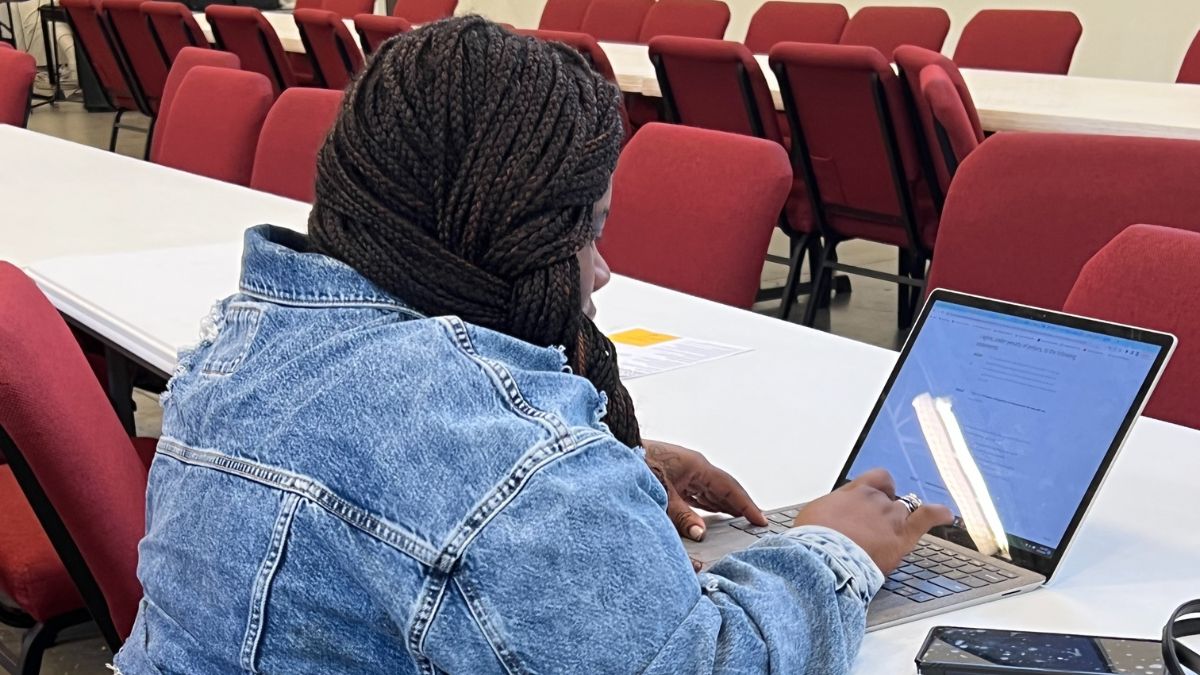 A woman sits in front of a laptop and enrolls in the Affordable Connectivity Program.