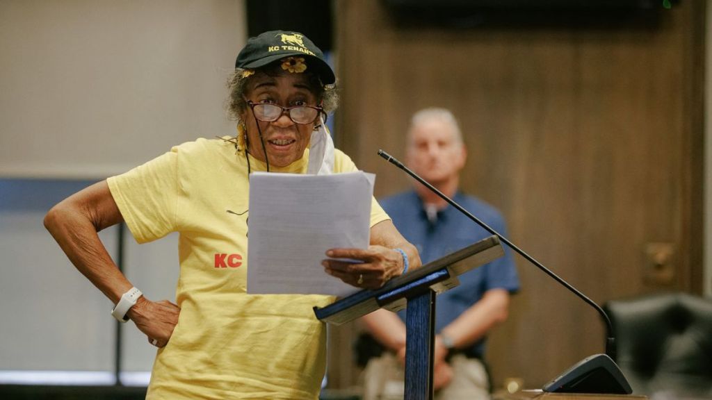 KC Tenants founding member Diane Charity speaks into the microphone at City Hall. Her hand is on her hip, and she's reading a written statement off of a paper.
