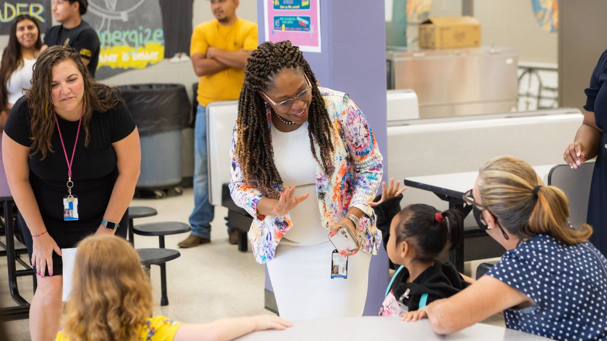 Adult woman and young child reach out to each other to high five or wave