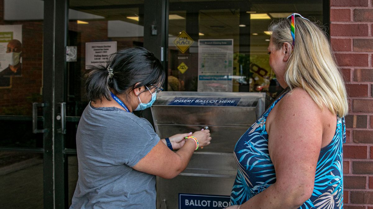 Two election workers lock a ballot box at the close of voting during the 2022 primary election in Wichita.