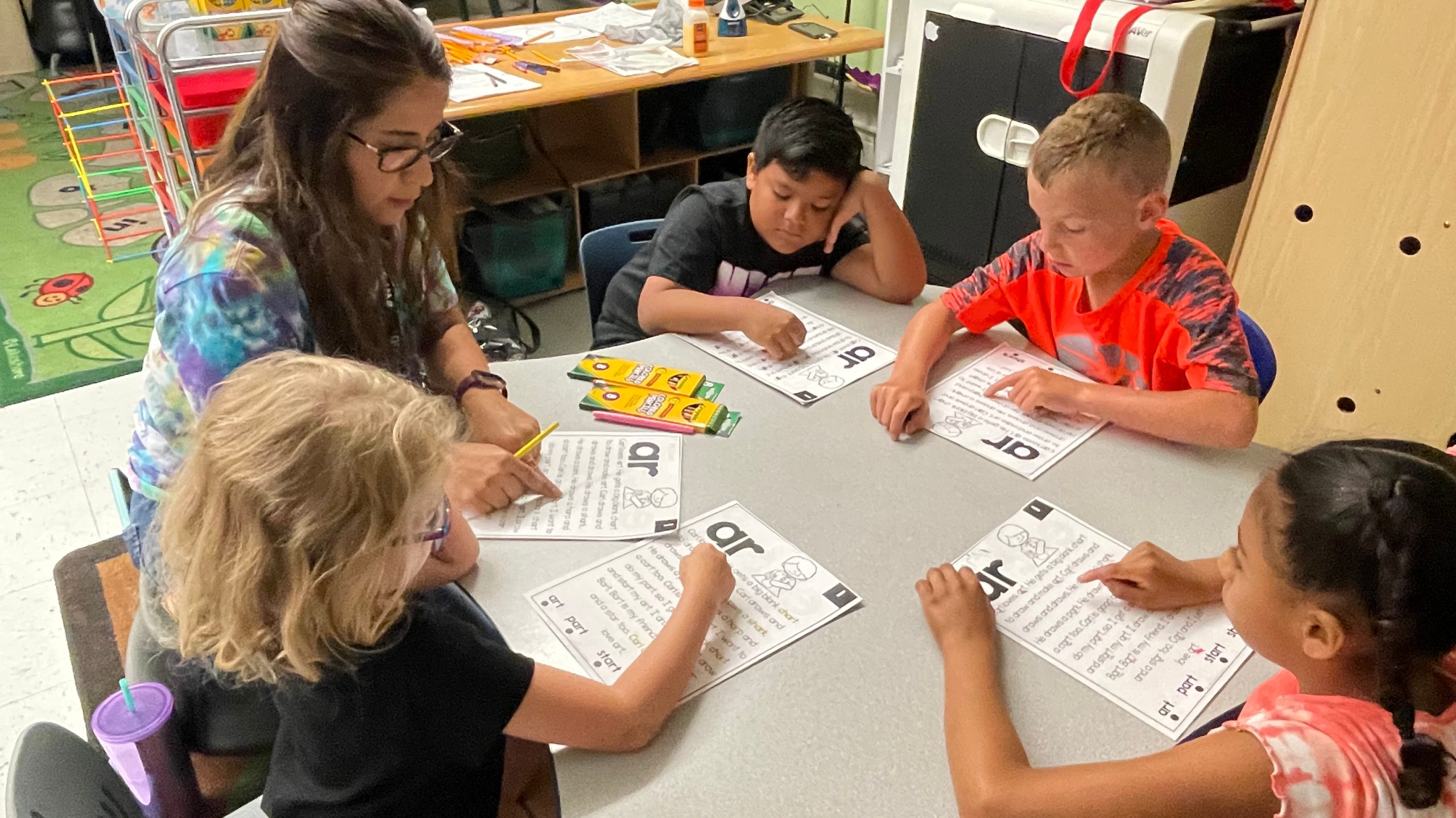 A teacher and four students working around a table.