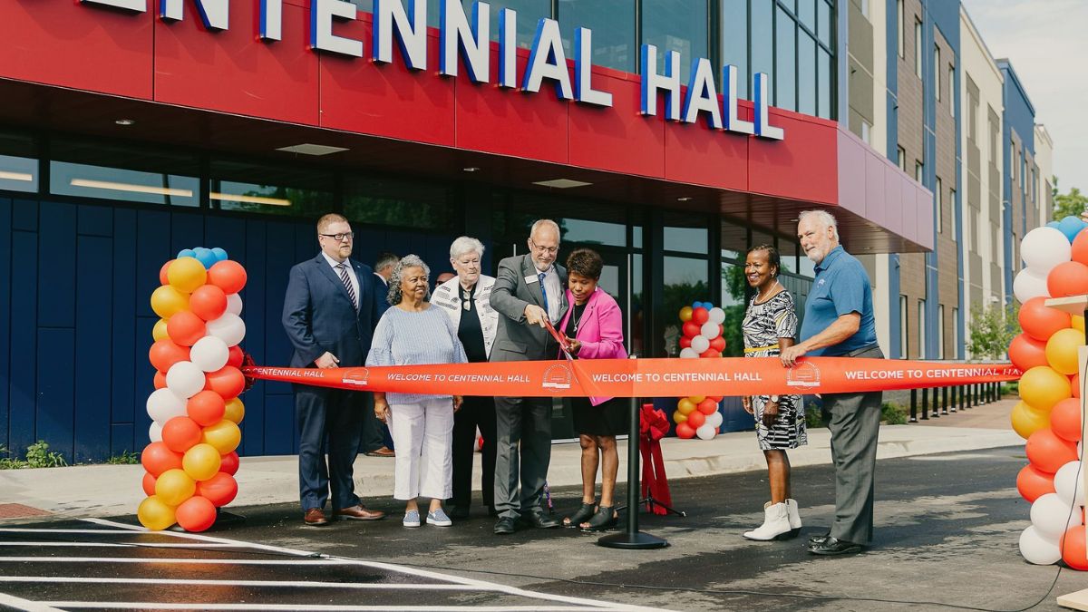 A group watches two KCKCC leaders cut a ribbon in front of Centennial Hall