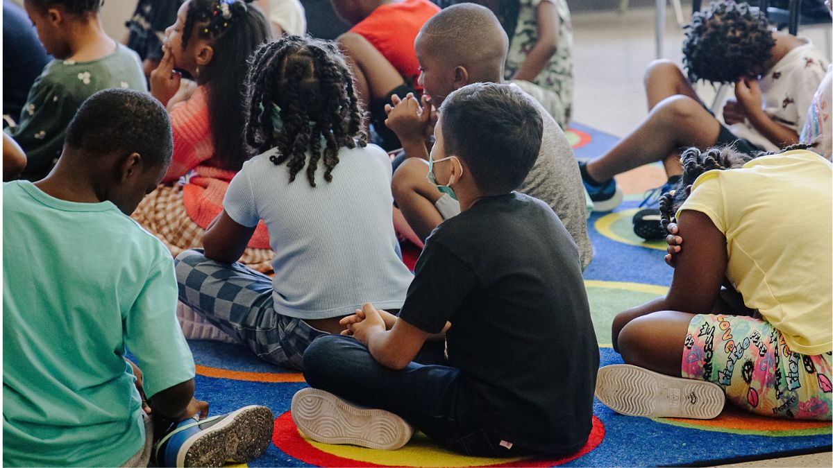 Children sit on a rug