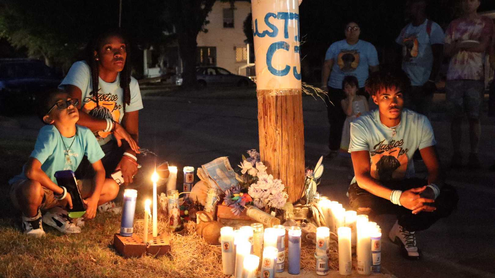 Gennieve Floyd, Cedric Lofton’s cousin, and Mark Teetz, Lofton’s brother, kneeling beside candles at a vigil for Cedric.