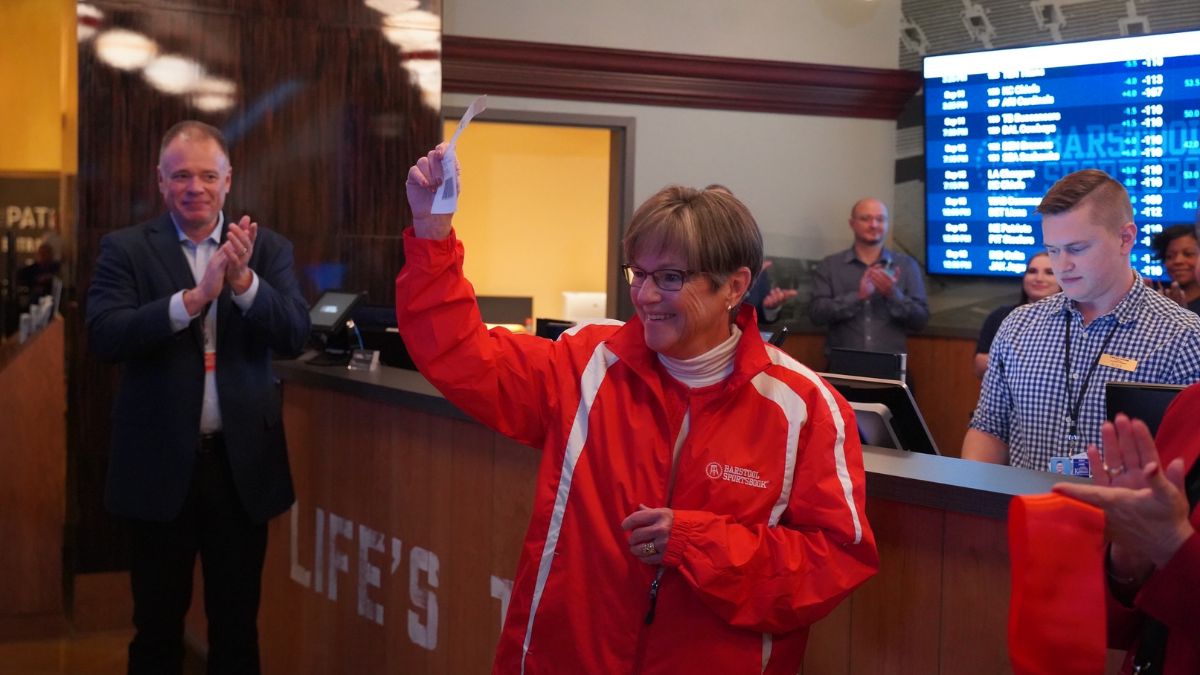 Kansas Gov. Laura Kelly stands in front of a sportsbook counter and celebrates placing the first legal sports bet in the state.