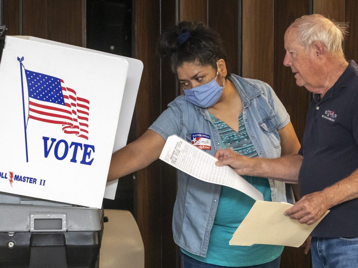 Poll worker helps voter during the 2023 Kansas primary election. In 2024, the county will spend more on polling sites but not mail-in ballots.