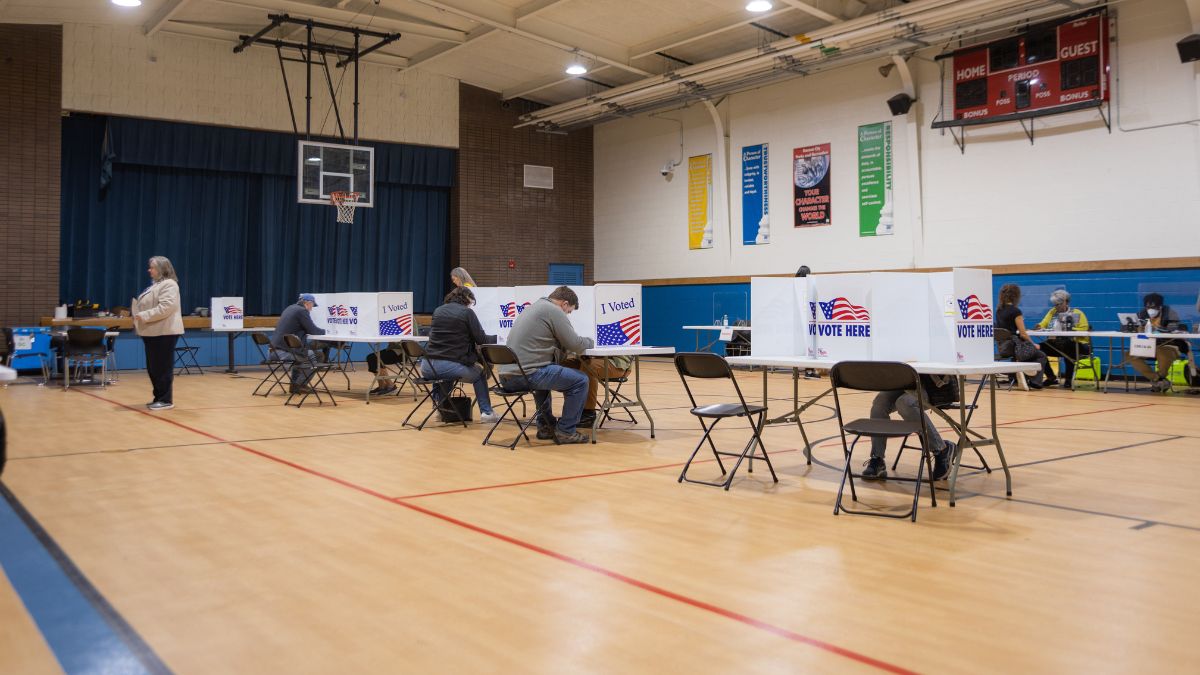 Roughly half a dozen voters complete ballots at polling stations inside a gymnasium.
