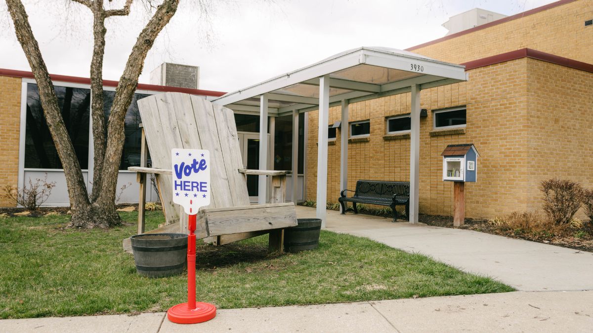 Exterior of the Kansas City North Community Center. A sign on the sidewalk says "Vote here" in blue letters.
