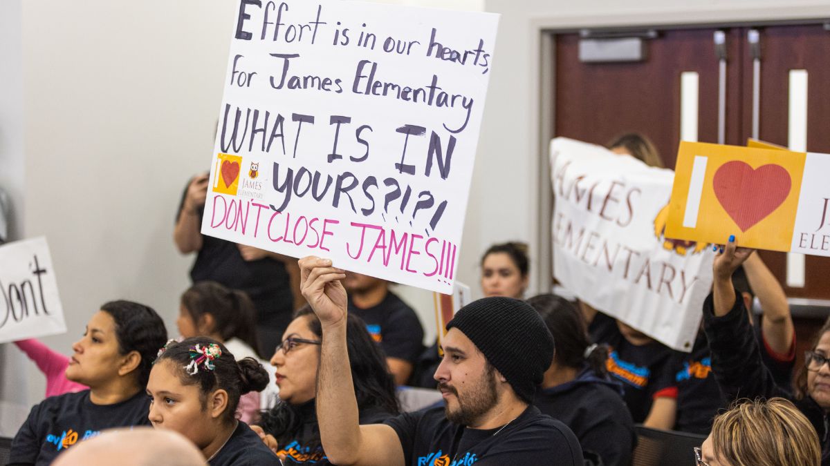 People holding signs. One reads 'Effort is in our hearts, for James Elementary. WHAT IS IN yours?!?! DON'T CLOSE JAMES!!!'