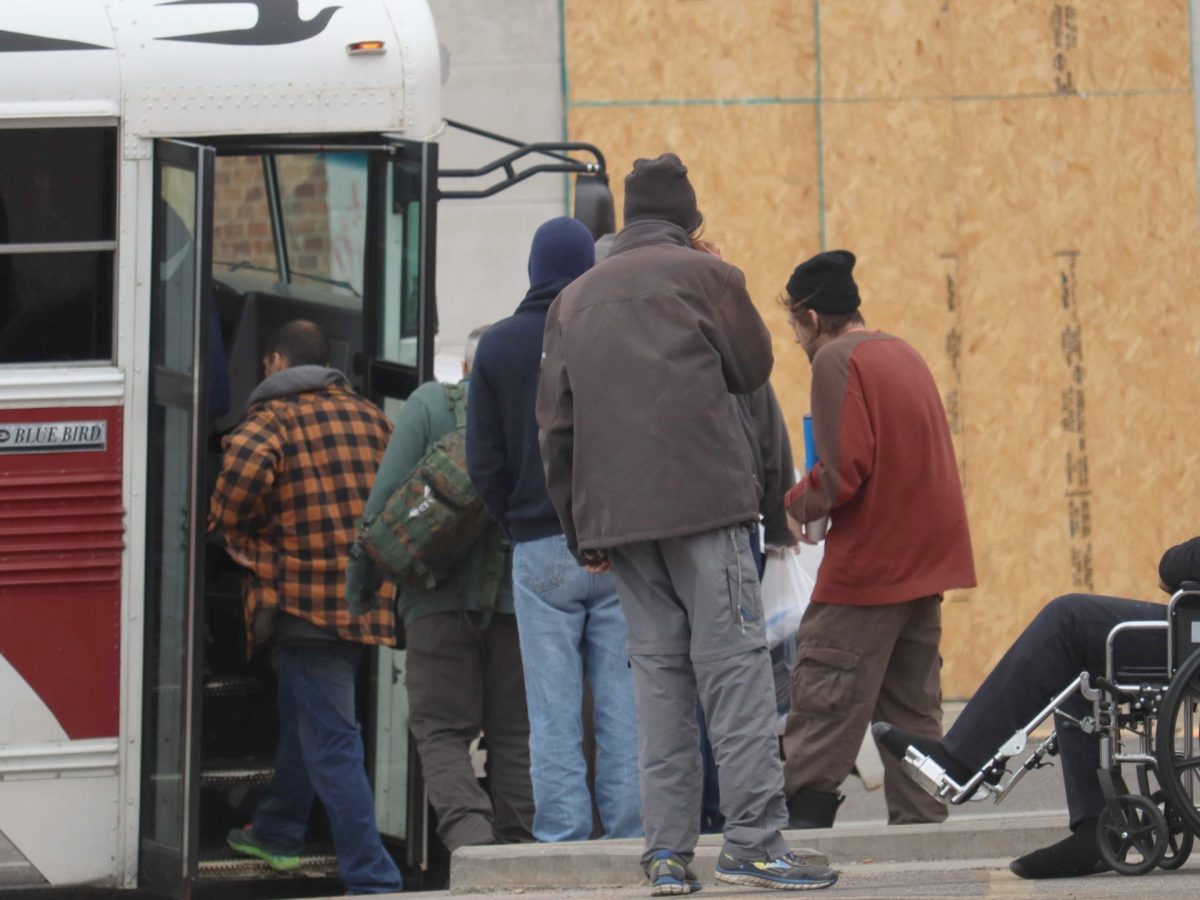 People lined up to get on a bus. The last one is in a wheelchair.