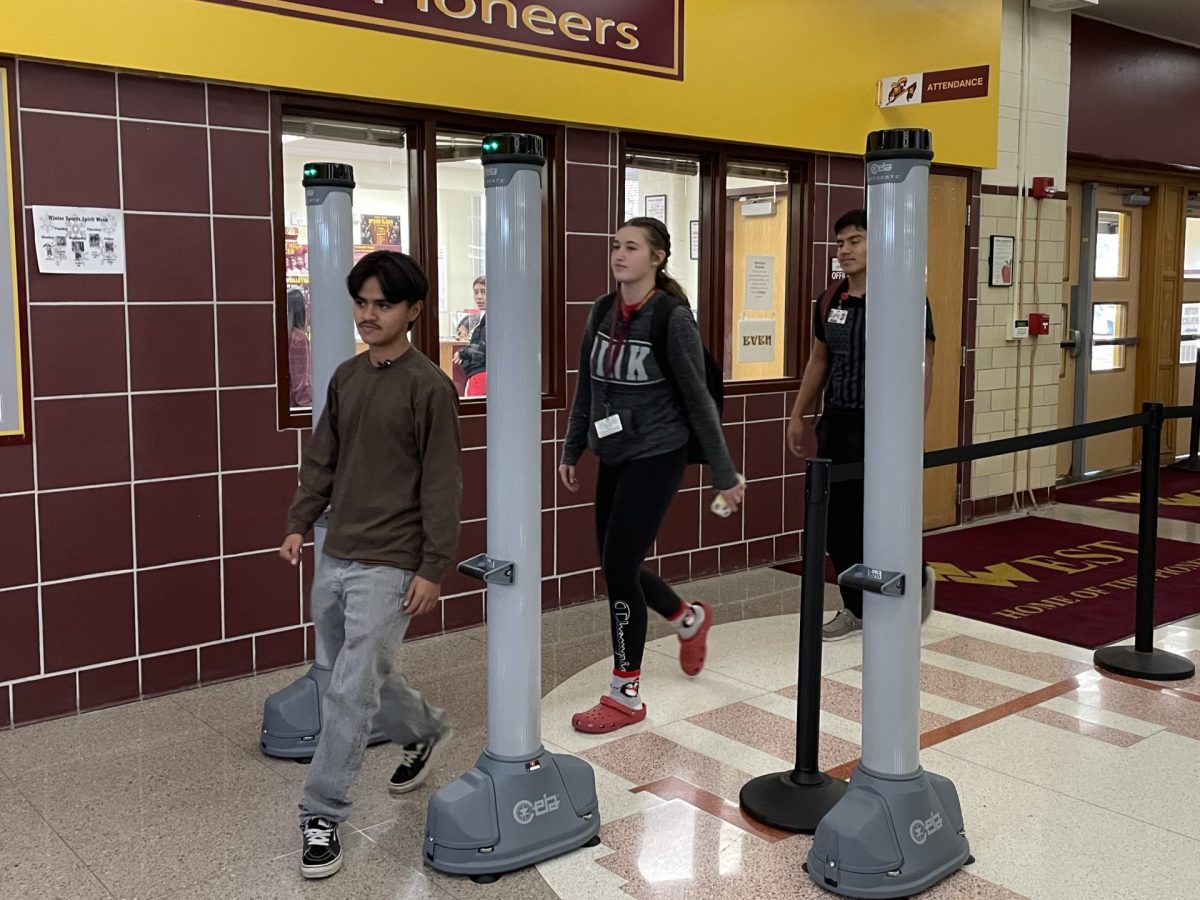 Two high school students walk through metal detectors at the entrance of a school. The detectors were added to increase school security.