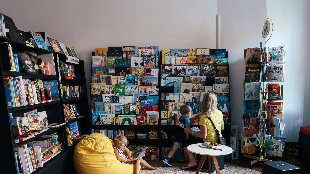 In a file photo, two children and a woman look at book shelves in a library.