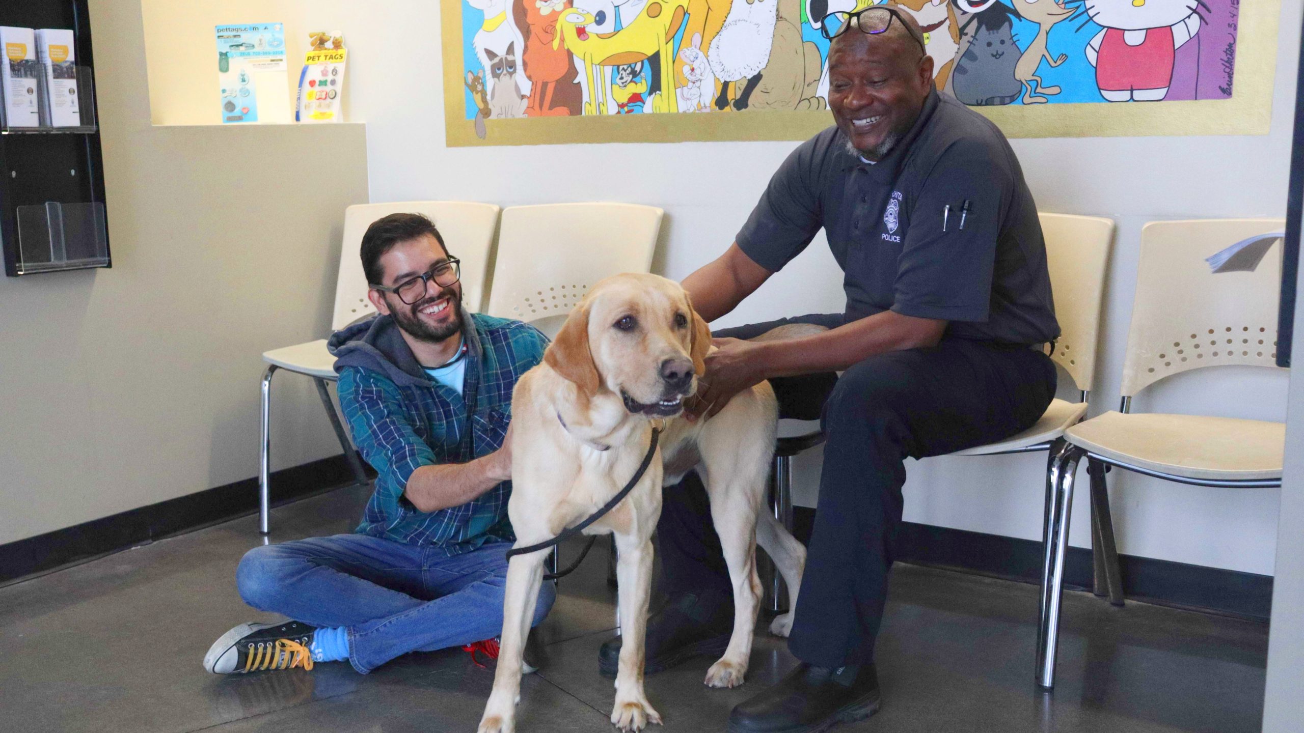 Two men sitting and petting a large dog.