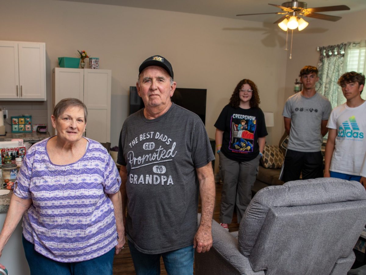 A retired couple in their small rental home with their three grandchildren to illustrate a story about downsizing tips for seniors.