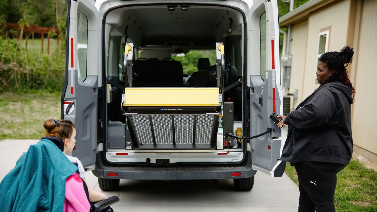 Ciassy Wilson helps Jenny Weitzel, who is in a wheelchair, get into a van that accommodates her wheelchair.