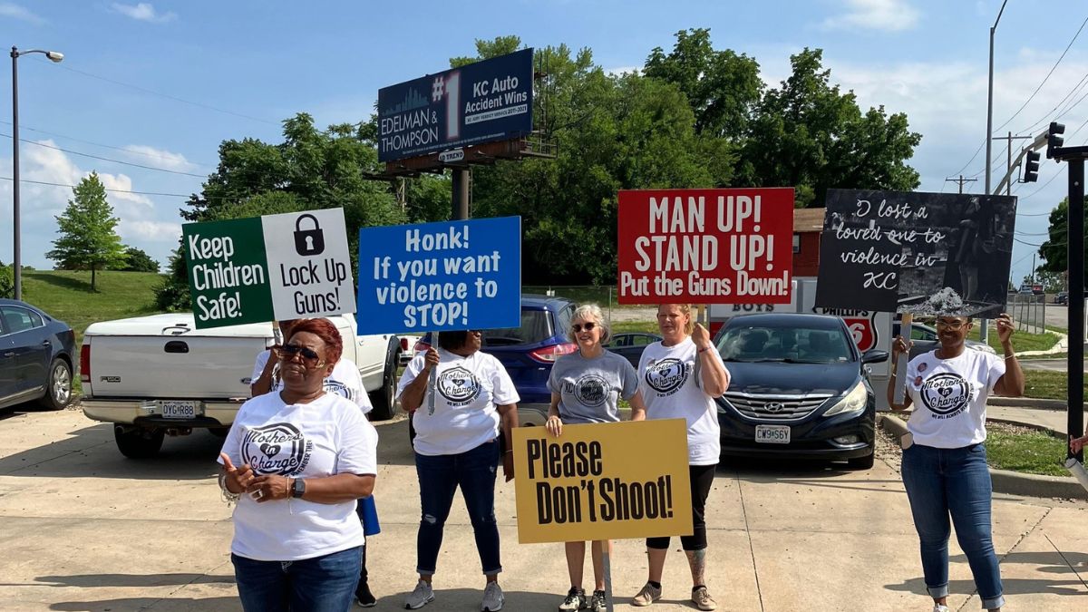 People stand in a parking lot in Kansas City holding signs to raise awareness about gun violence.