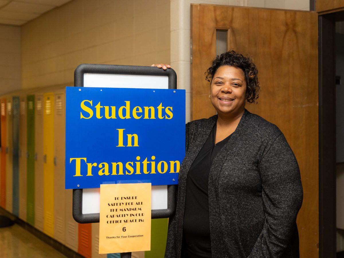 Melissa Douglas near a Students in Transition sign. The office works to remove barriers for homeless students.