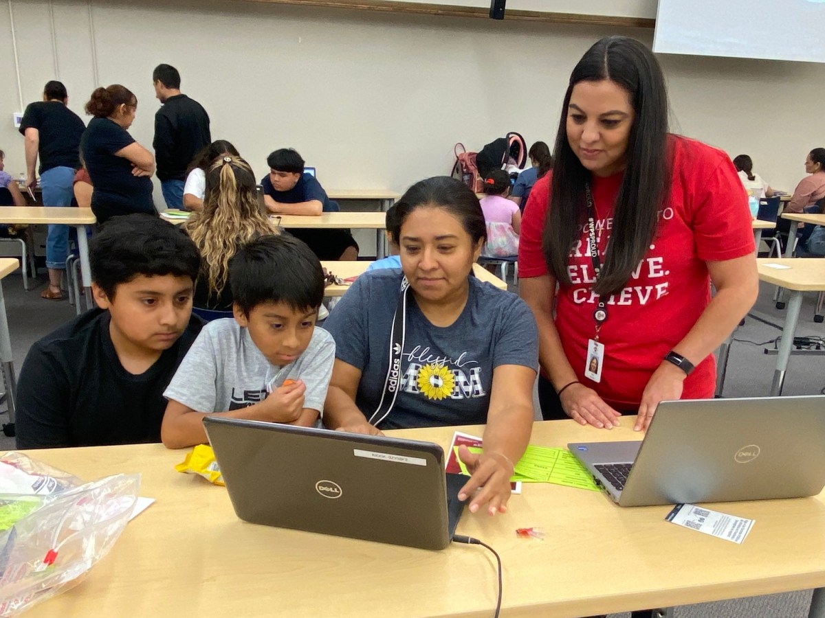 A worker helps a mom enroll her two kids.