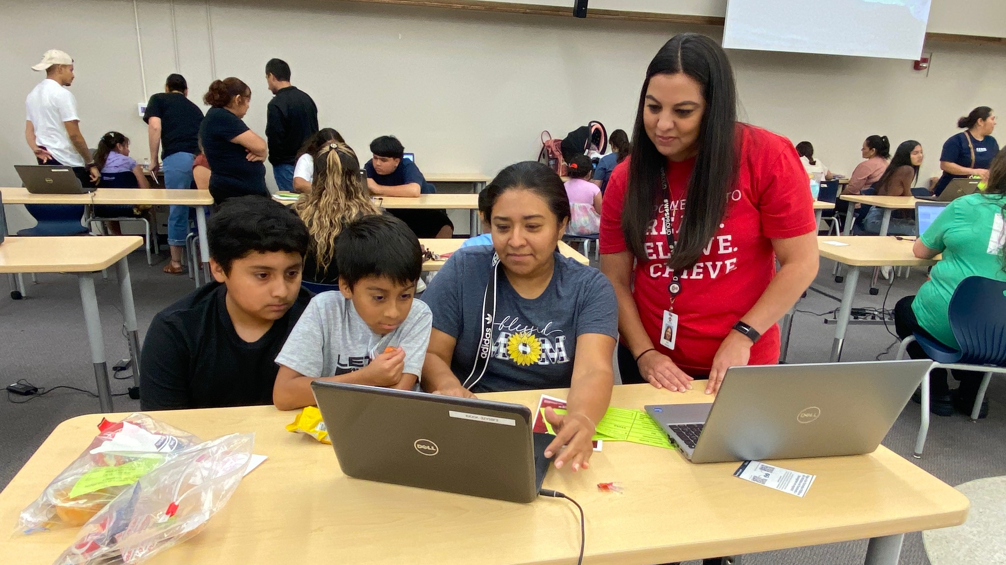 A worker helps a mom enroll her two kids.