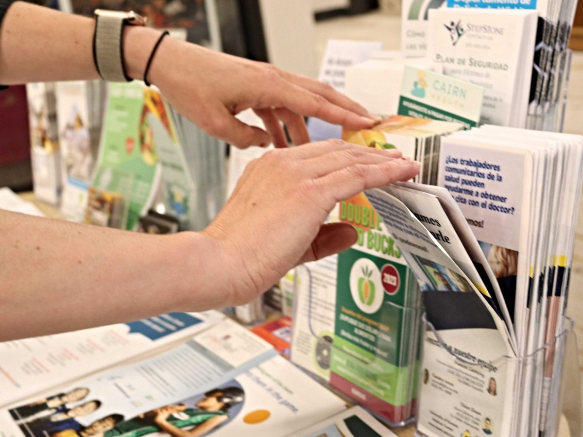 Hands reaching over to look through paper, bilingual brochures.