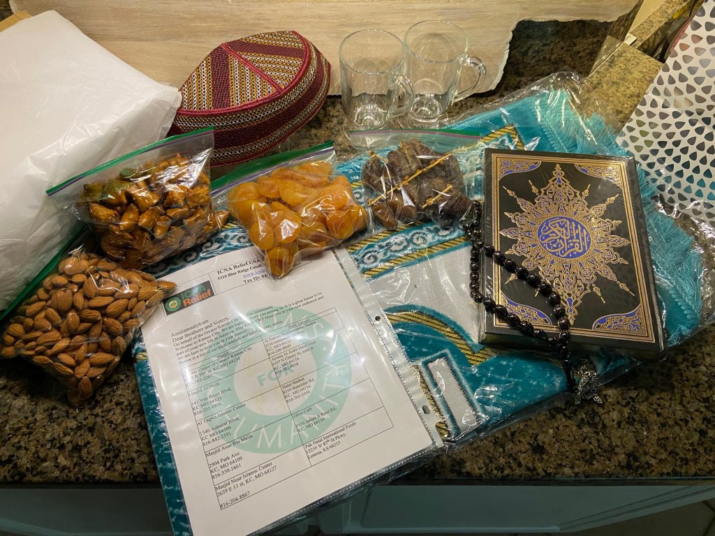 A portrait of snacks, a prayer mat, a Quran and prayer beads ready to be packaged for the welcome baskets.
