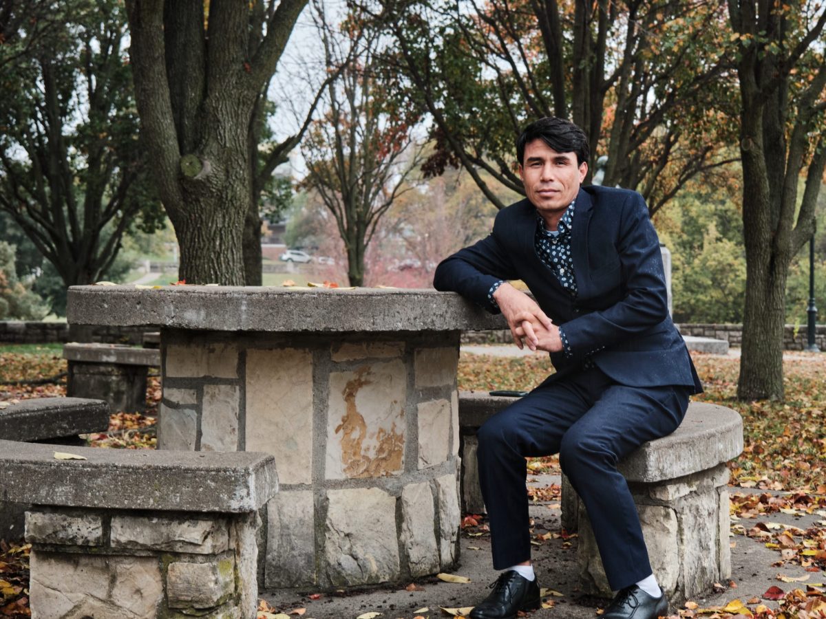 Qasim Rahimi sits outside in a park.