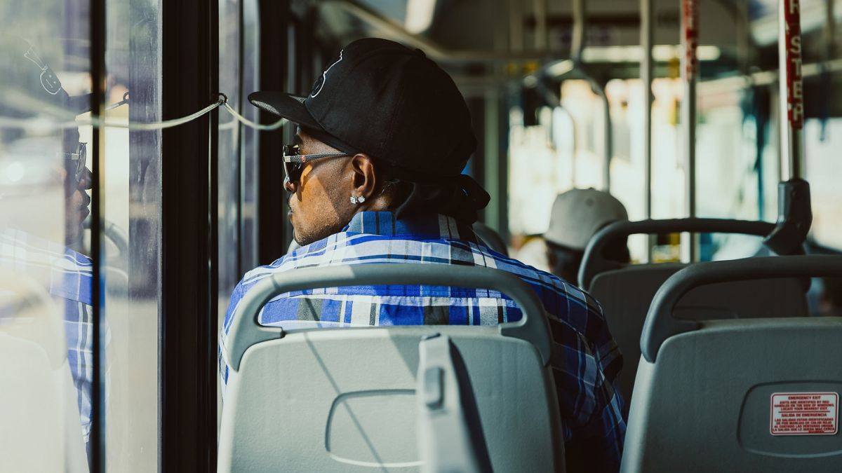 A seated bus rider looking out the window to their left.