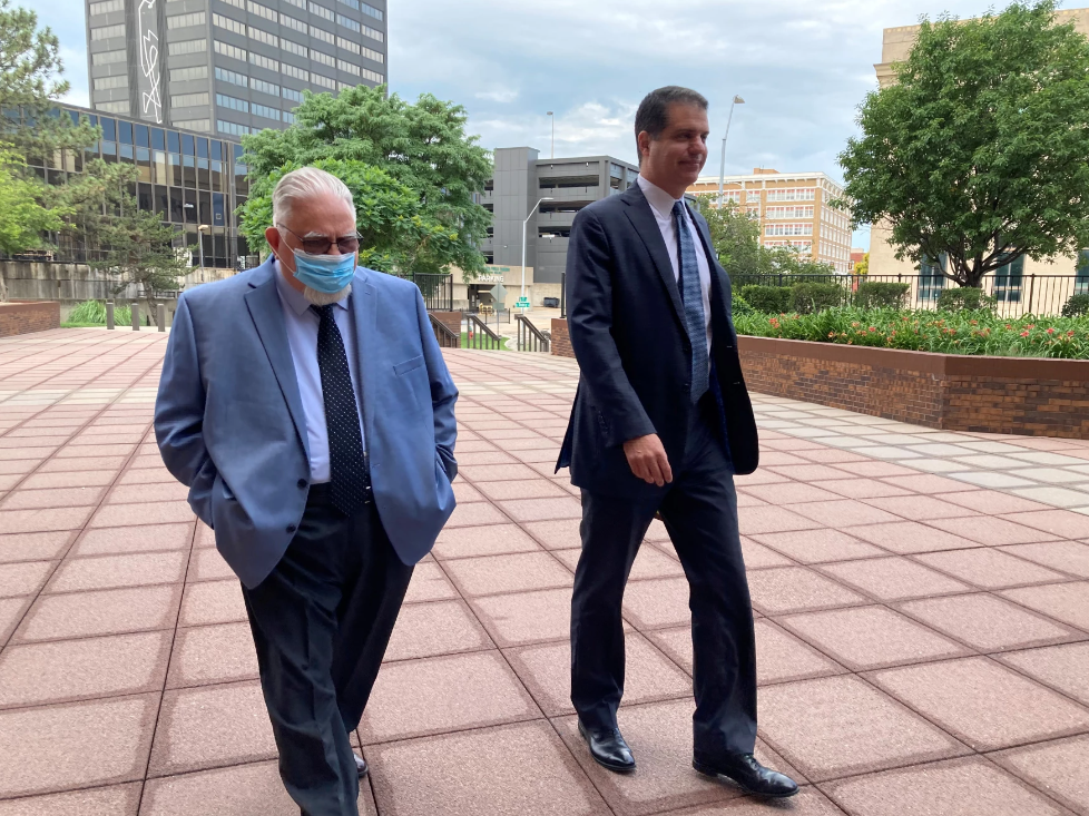 Two men walking in front of a courthouse.