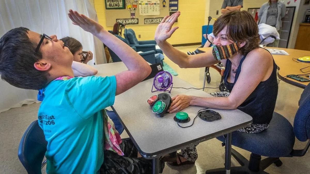 A speech pathologist high-fives a student