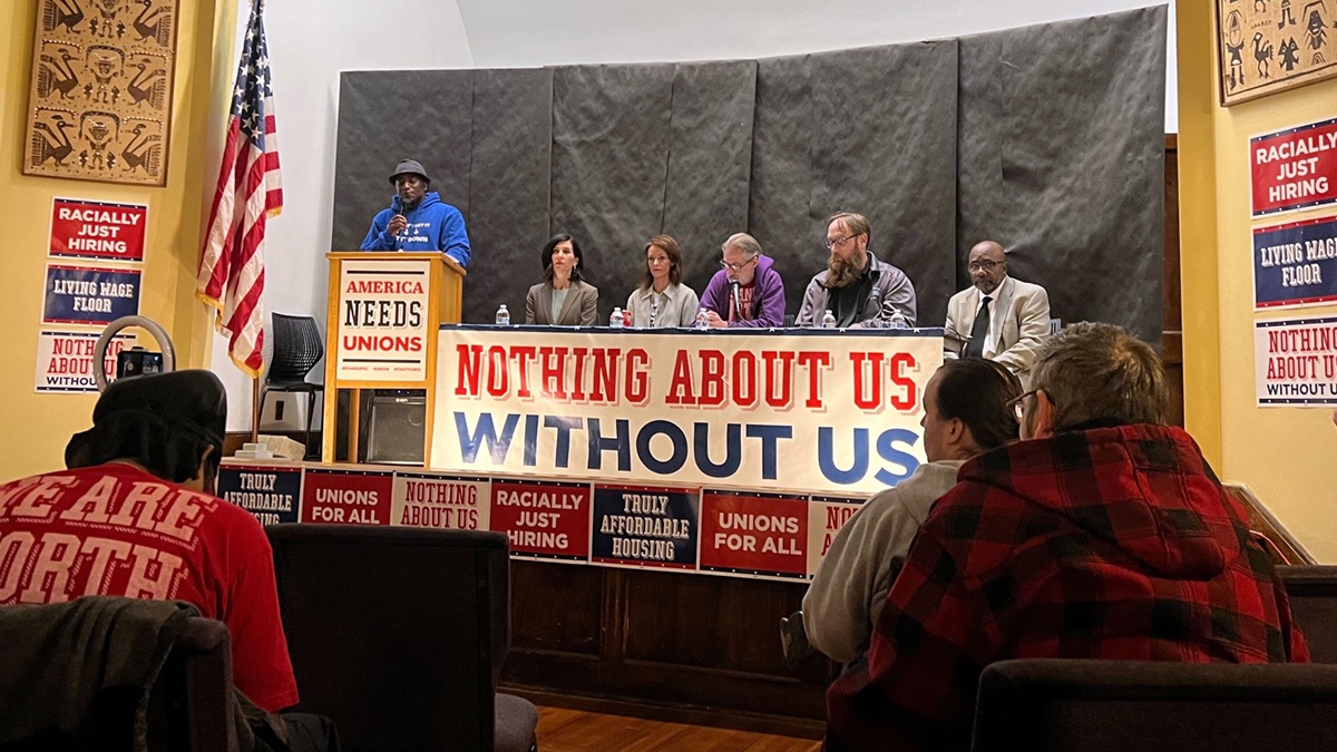Members of the Good Jobs and Affordable Housing for All Coalition sit on top of a stage during a February town hall and panel.