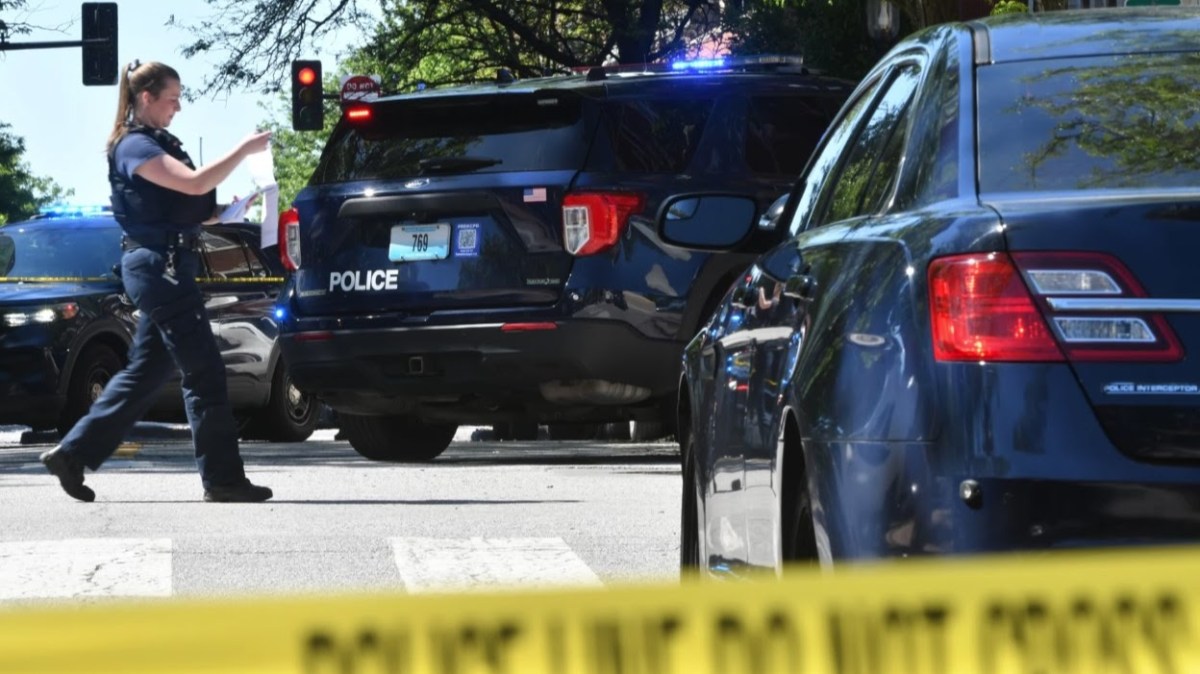 A police officer walking in front of crime tape.