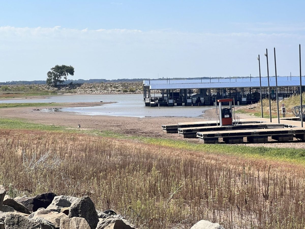 A fuel dock sits on dry land at Cheney Lake. A marina with several boats sits on a couple inches of water in the background.